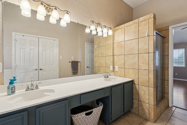 full bathroom featuring a sink, tile patterned flooring, a shower stall, and double vanity