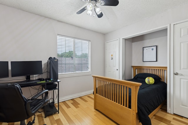 bedroom featuring baseboards, a textured ceiling, light wood finished floors, and ceiling fan
