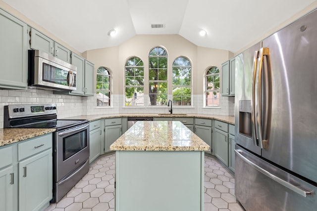 kitchen with visible vents, a kitchen island, a sink, vaulted ceiling, and stainless steel appliances