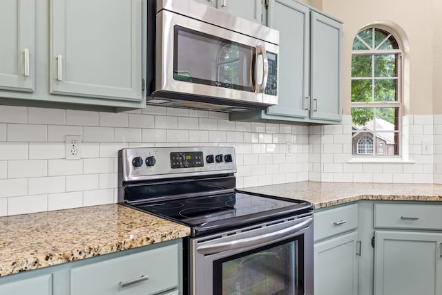 kitchen featuring backsplash, light stone countertops, and appliances with stainless steel finishes