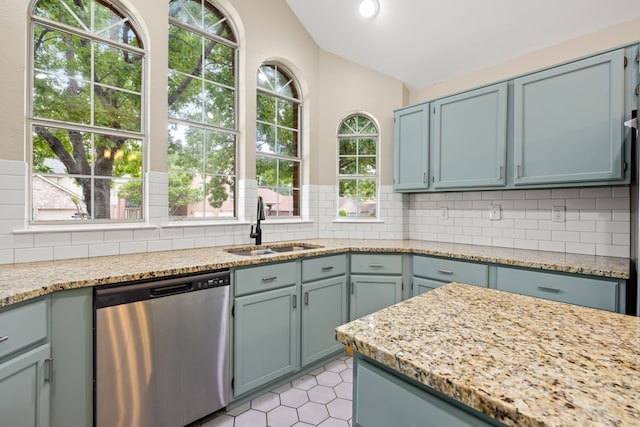 kitchen featuring stainless steel dishwasher, vaulted ceiling, decorative backsplash, and a sink