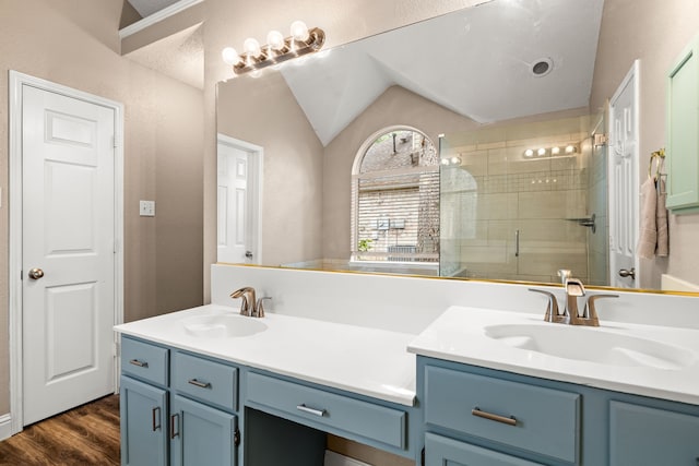 full bathroom with double vanity, a sink, a stall shower, and vaulted ceiling