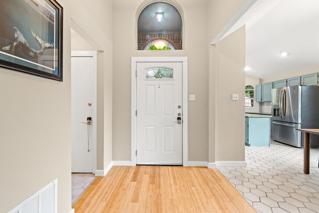 foyer entrance with baseboards, visible vents, and light wood-style flooring