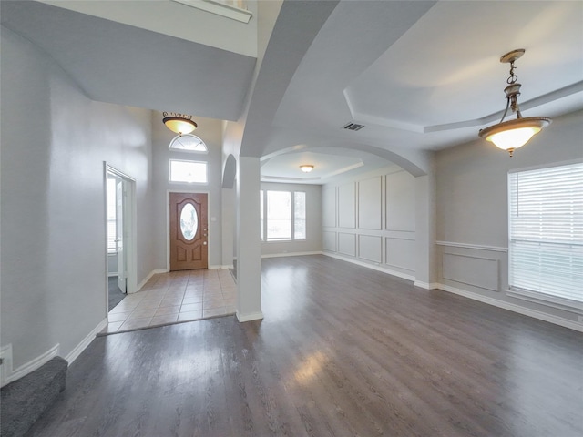 foyer with arched walkways, baseboards, and wood finished floors
