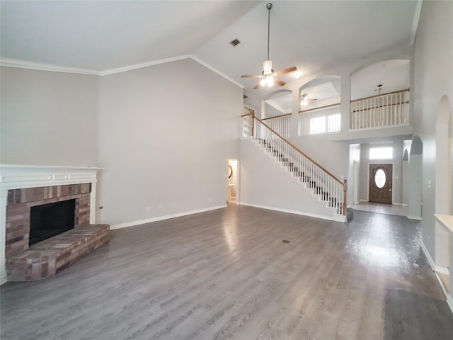unfurnished living room featuring a ceiling fan, stairs, wood finished floors, and high vaulted ceiling