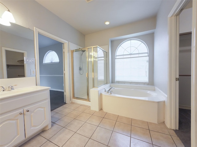 bathroom with tile patterned flooring, a garden tub, vanity, a walk in closet, and a stall shower
