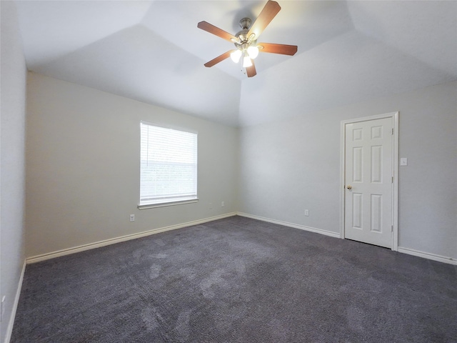 empty room featuring dark carpet, baseboards, ceiling fan, and vaulted ceiling