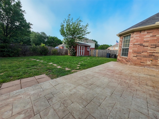 view of yard featuring an outbuilding, a fenced backyard, a patio area, and a storage unit