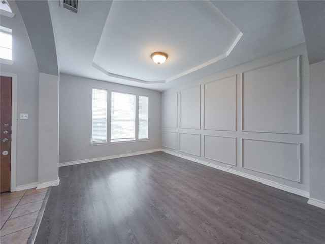 interior space featuring visible vents, plenty of natural light, wood finished floors, and a raised ceiling