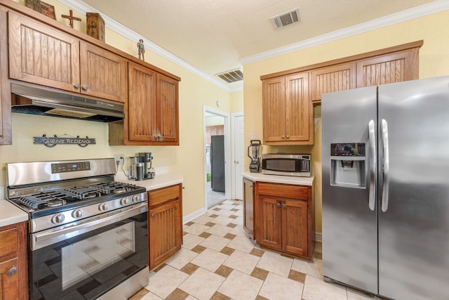 kitchen featuring under cabinet range hood, appliances with stainless steel finishes, ornamental molding, and visible vents