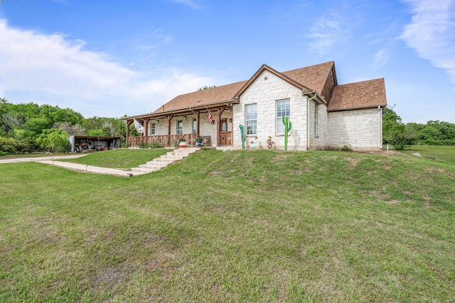 ranch-style home featuring a porch, a shingled roof, a front yard, and stone siding