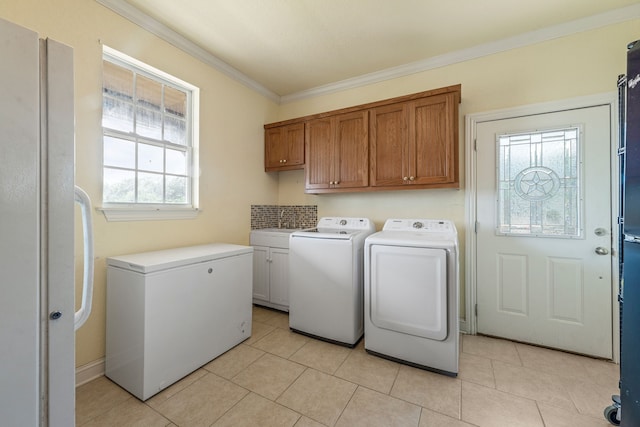 laundry area featuring cabinet space, light tile patterned flooring, washing machine and dryer, and ornamental molding