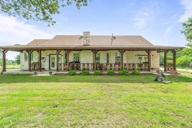 rear view of property featuring a lawn, a chimney, and stone siding