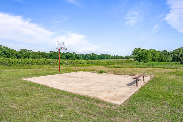 view of basketball court with a yard and basketball hoop