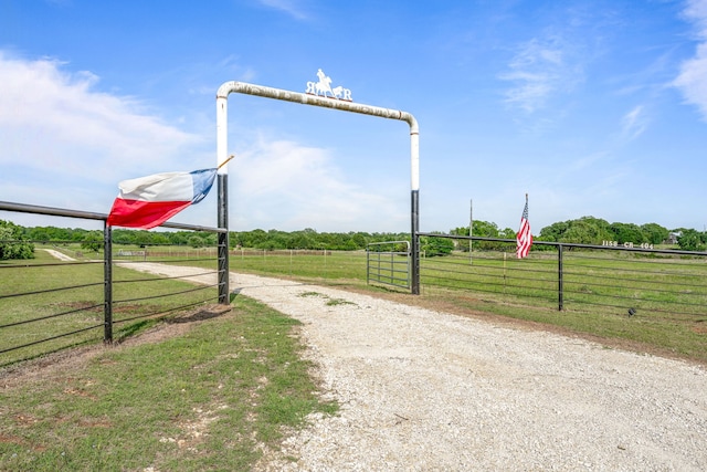 view of road with a gated entry, a rural view, and gravel driveway