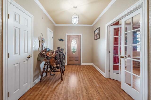 foyer with baseboards, light wood-style flooring, crown molding, and french doors