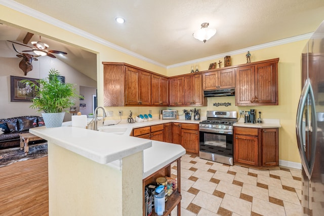 kitchen featuring a sink, a peninsula, under cabinet range hood, a ceiling fan, and appliances with stainless steel finishes