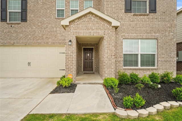 entrance to property featuring brick siding and driveway
