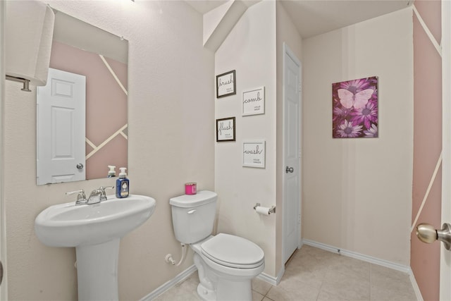 half bath with baseboards, tile patterned floors, and toilet
