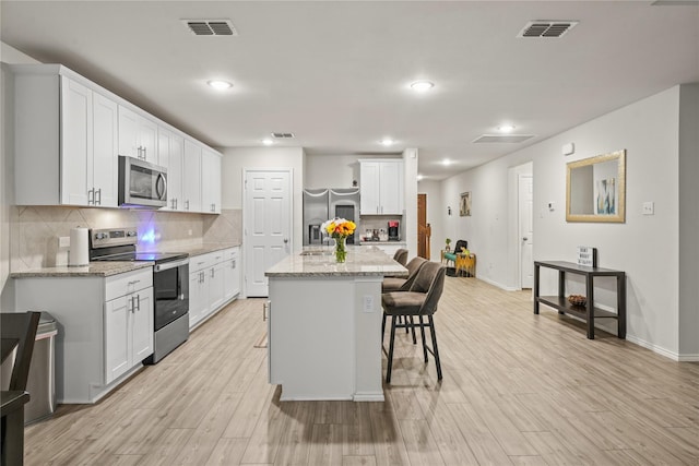 kitchen featuring visible vents, appliances with stainless steel finishes, a kitchen breakfast bar, and light wood-type flooring
