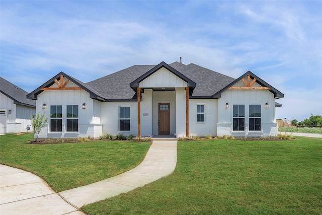 modern inspired farmhouse featuring board and batten siding, brick siding, roof with shingles, and a front lawn