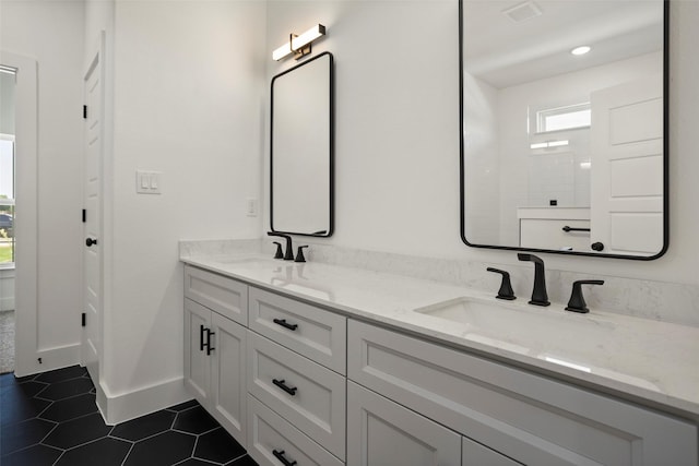 full bath featuring double vanity, a sink, baseboards, and tile patterned floors