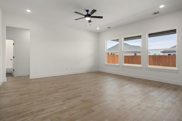 spare room with ceiling fan, visible vents, baseboards, and light wood-style floors