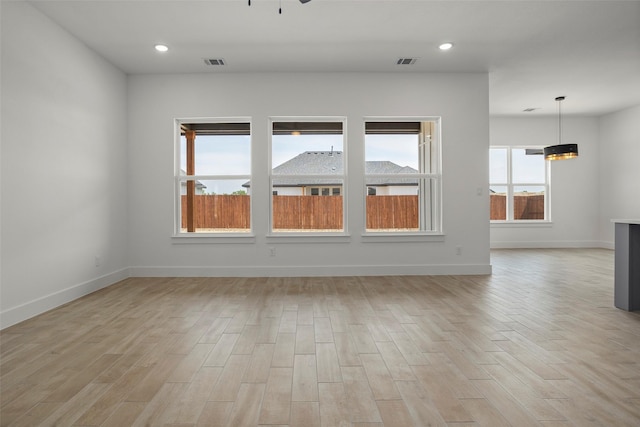 empty room with baseboards, visible vents, and light wood finished floors