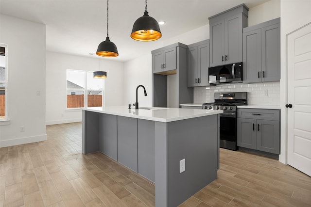 kitchen with light wood-style floors, light countertops, gray cabinets, stainless steel appliances, and tasteful backsplash