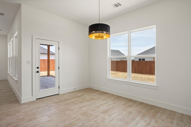 unfurnished dining area with baseboards, visible vents, and light wood-style flooring