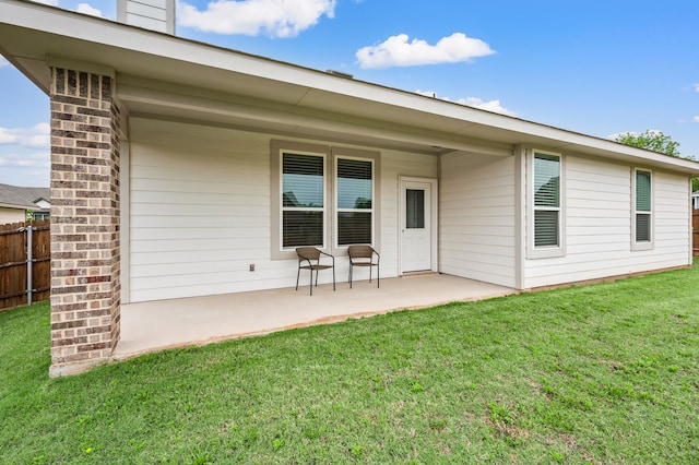 rear view of property with a lawn, fence, a chimney, and a patio area