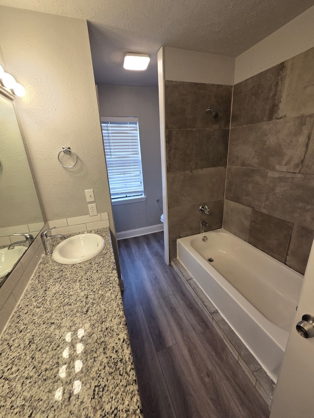 bathroom featuring vanity, shower / bathtub combination, toilet, a textured ceiling, and baseboards