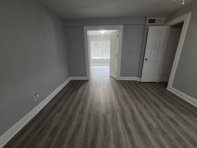 spare room featuring baseboards, dark wood-style floors, and visible vents