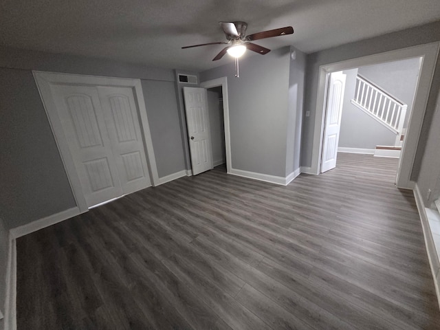 interior space featuring dark wood-style flooring, ceiling fan, visible vents, and baseboards