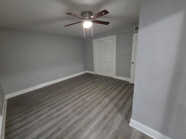 empty room with baseboards, dark wood-type flooring, ceiling fan, and visible vents