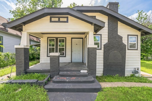 view of front of house featuring a chimney and a porch