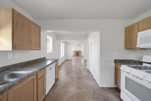 kitchen featuring dark countertops, a sink, a fireplace, white appliances, and baseboards