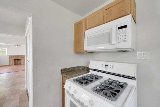 kitchen with white appliances, a ceiling fan, a fireplace, and light brown cabinets