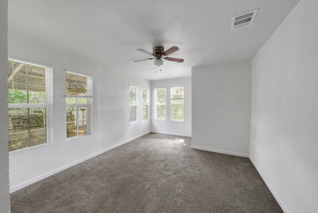 carpeted spare room featuring ceiling fan, visible vents, and baseboards