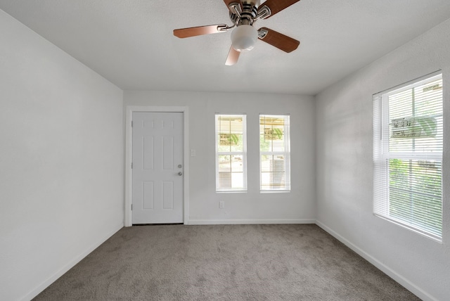 carpeted empty room with plenty of natural light, baseboards, and ceiling fan