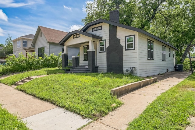 bungalow with central AC unit and a chimney
