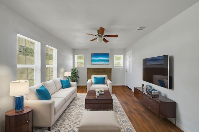 living room featuring baseboards, a ceiling fan, wood finished floors, and visible vents