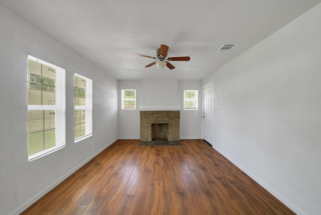 unfurnished living room with visible vents, a brick fireplace, baseboards, ceiling fan, and dark wood-style floors