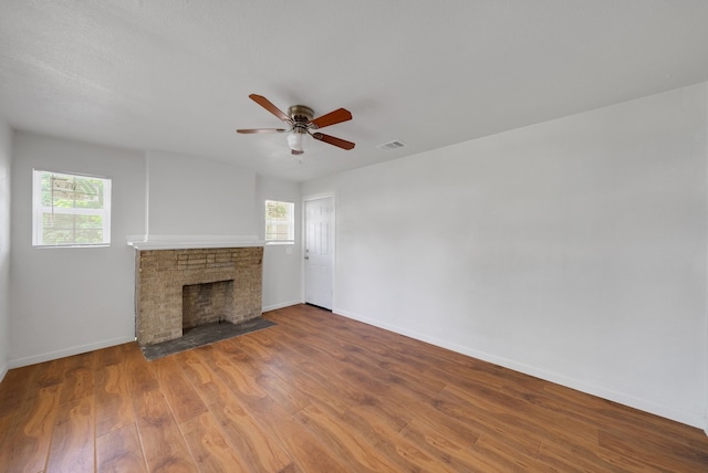 unfurnished living room with baseboards, a wealth of natural light, wood finished floors, and a fireplace