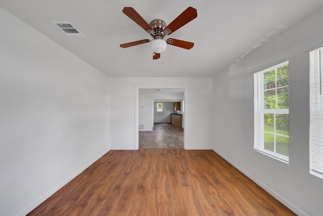empty room with ceiling fan, baseboards, visible vents, and wood finished floors