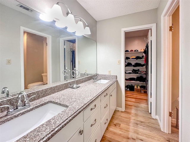 104 W Perry St, Frankston, TX 75763 - full bath featuring toilet, a textured ceiling, a sink, and wood finished floors