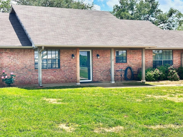 104 W Perry St, Frankston, TX 75763 - rear view of house with a lawn, brick siding, and roof with shingles
