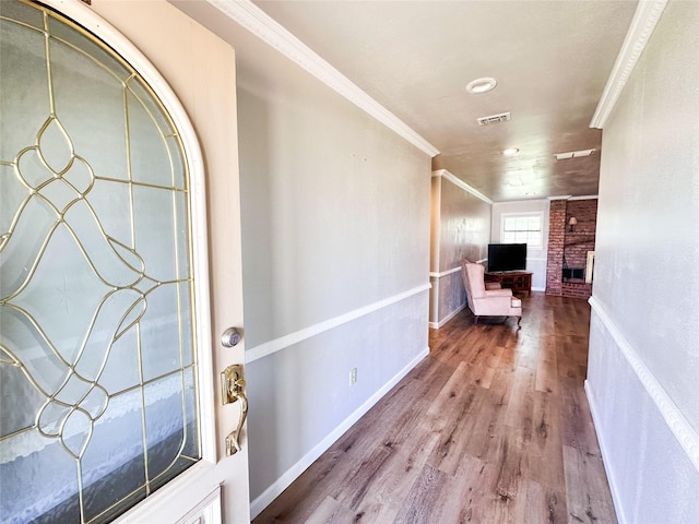 104 W Perry St, Frankston, TX 75763 - entrance foyer featuring crown molding, a brick fireplace, baseboards, wood finished floors, and visible vents