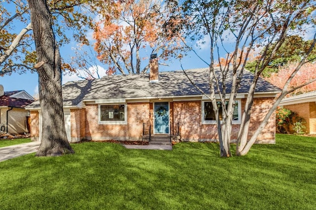 ranch-style home with a chimney, a front yard, roof with shingles, brick siding, and entry steps