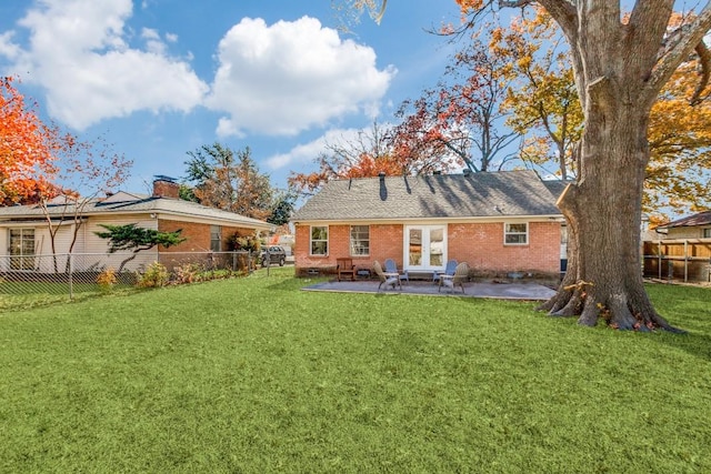 back of property with a fenced backyard, french doors, brick siding, a patio area, and a lawn